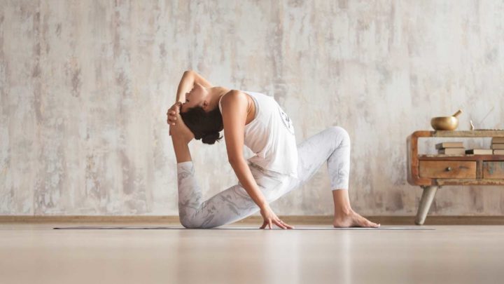 Yoga teacher practices yoga in her living room.